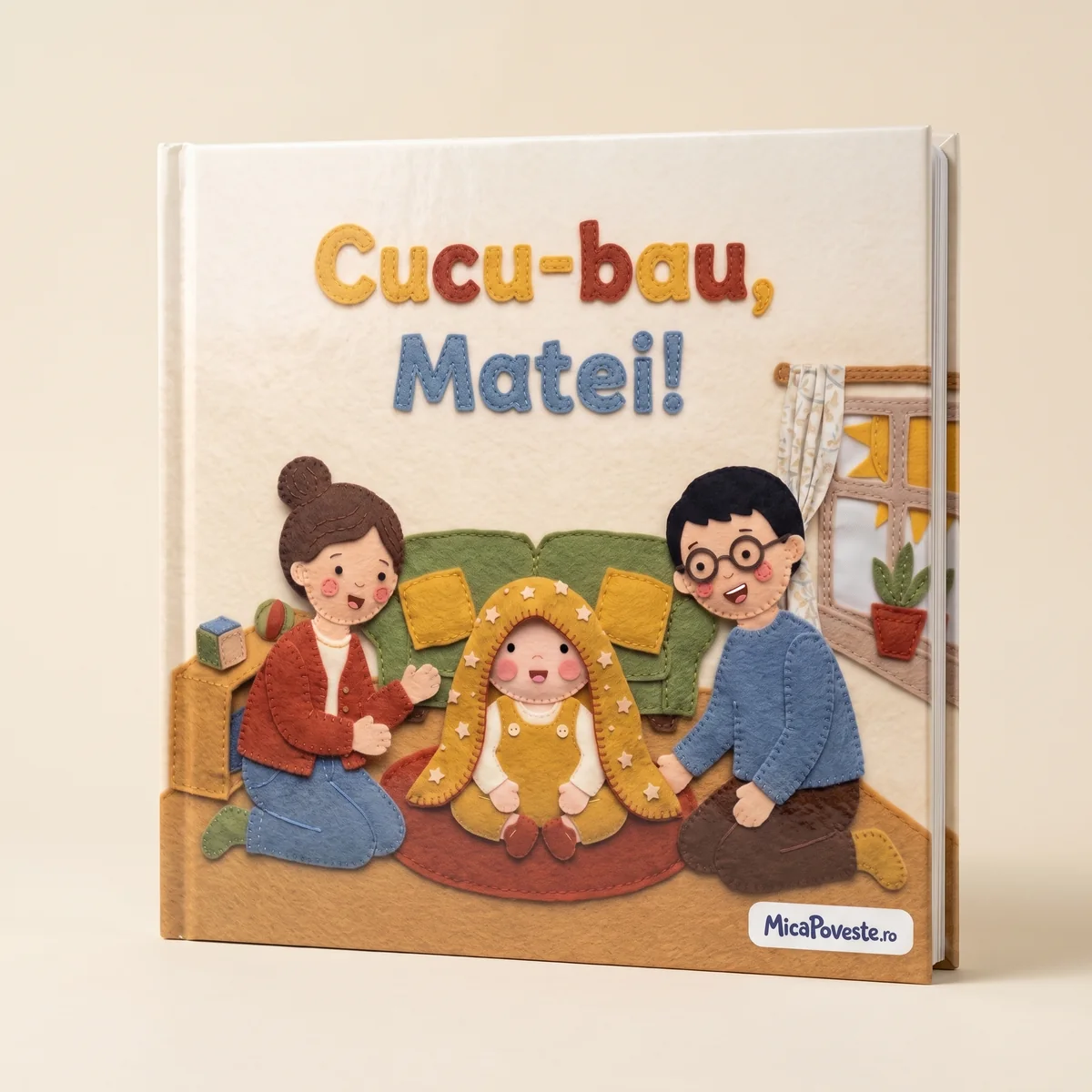 Cartea „Cucu-bau, Matei!”, cu copertă tare. Pe copertă: Matei apare de sub pătura cu stele, iar Mama și Tata râd lângă el, pe covor